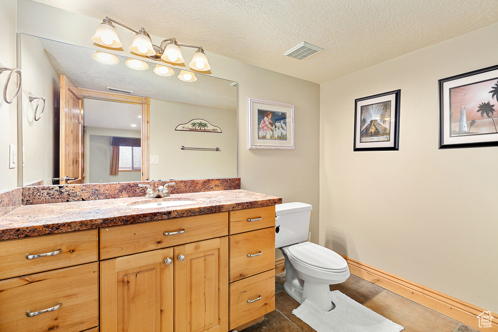 Bathroom with tile floors, a textured ceiling, toilet, and vanity