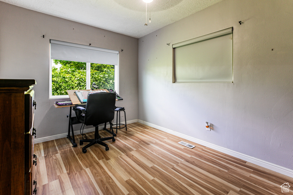 Office area with light hardwood / wood-style floors and a textured ceiling