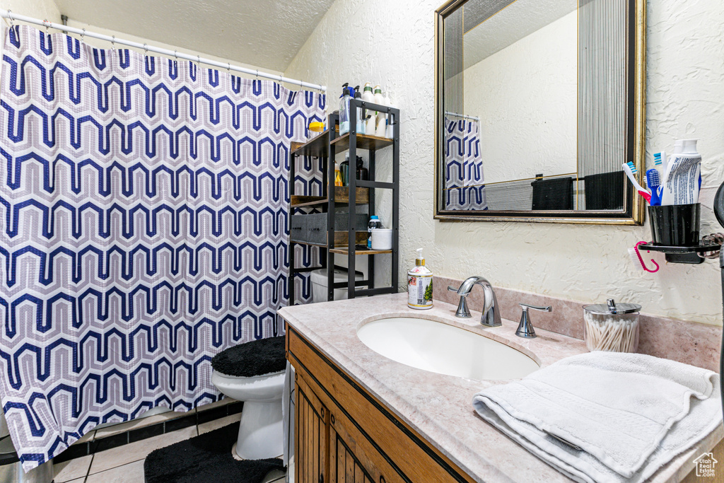 Bathroom with tile flooring, oversized vanity, toilet, and a textured ceiling