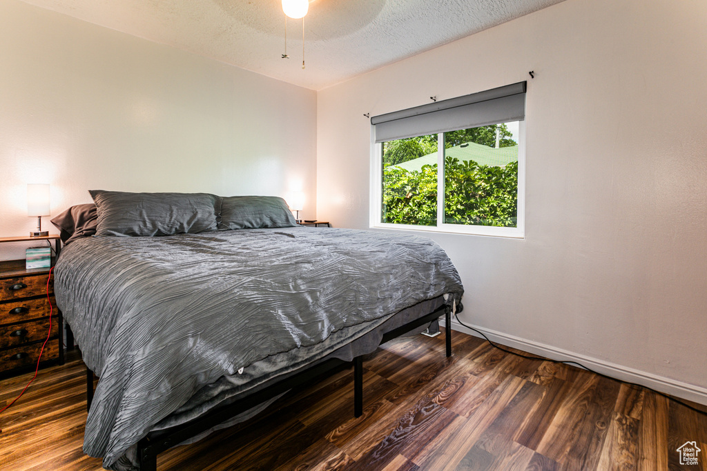 Bedroom featuring a textured ceiling, dark wood-type flooring, and ceiling fan