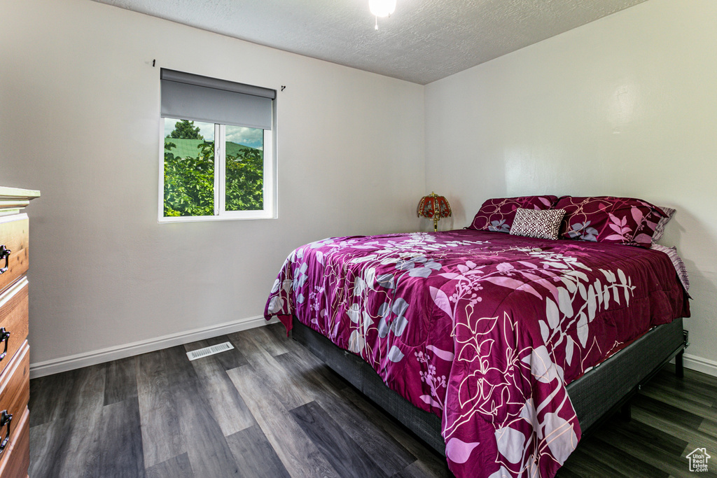 Bedroom with a textured ceiling and dark wood-type flooring