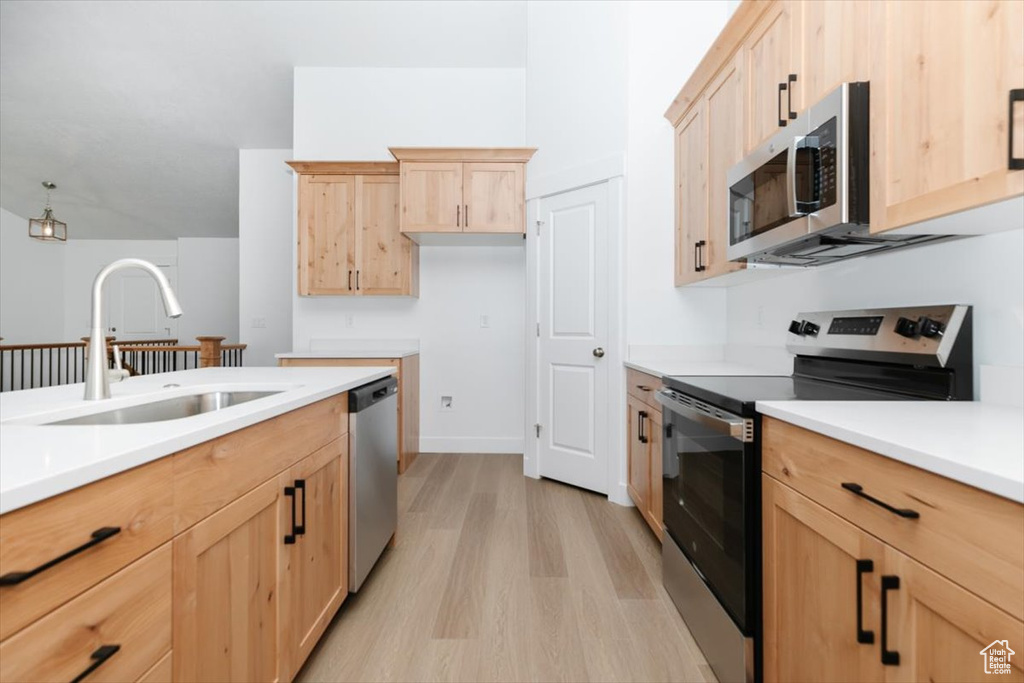 Kitchen with light brown cabinetry, stainless steel appliances, light wood-type flooring, and sink