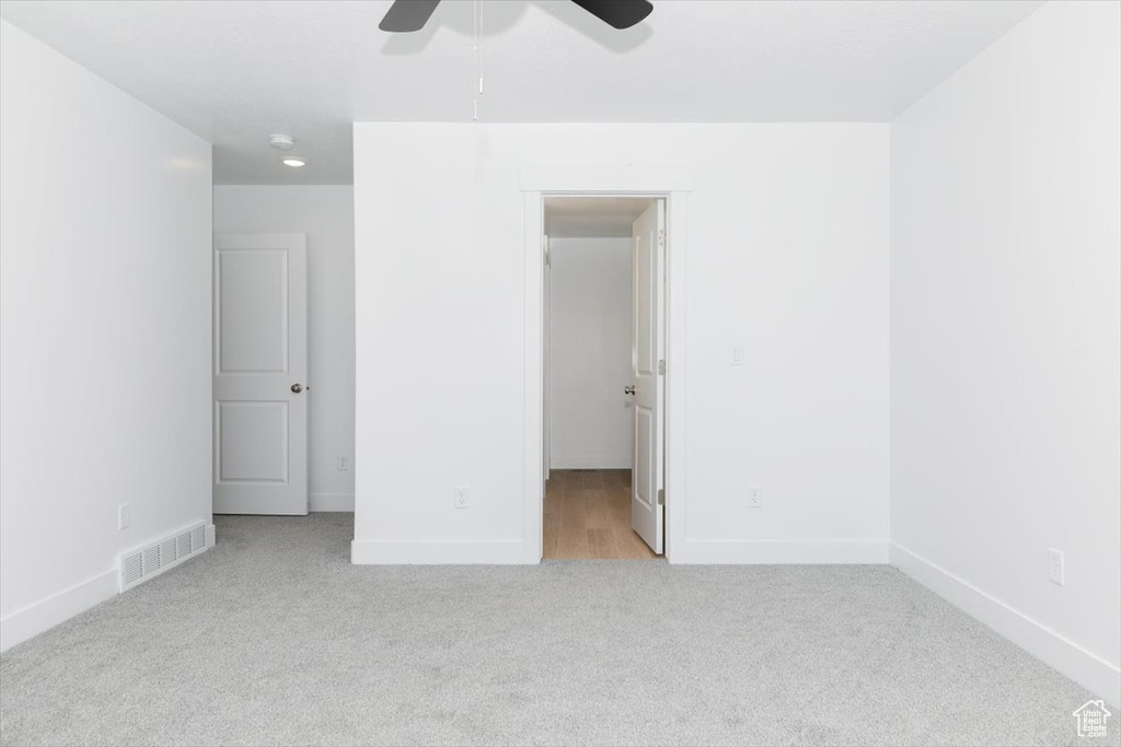 Unfurnished bedroom with ceiling fan and light carpet