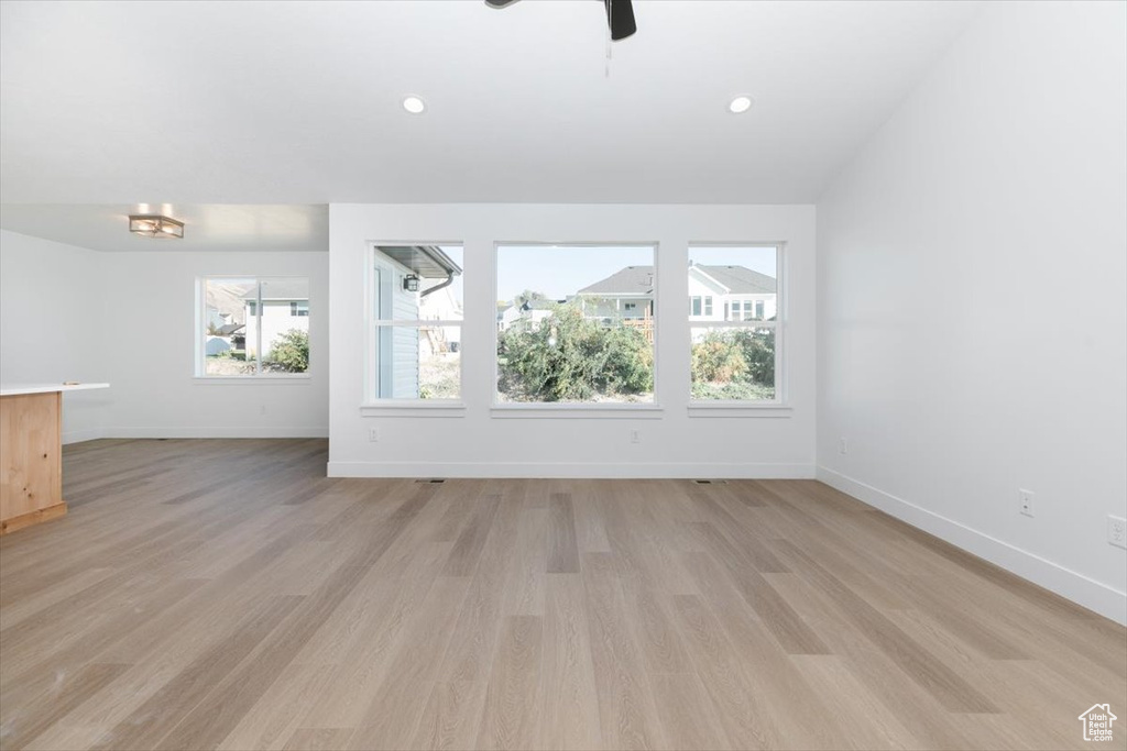 Unfurnished living room with light wood-type flooring and ceiling fan