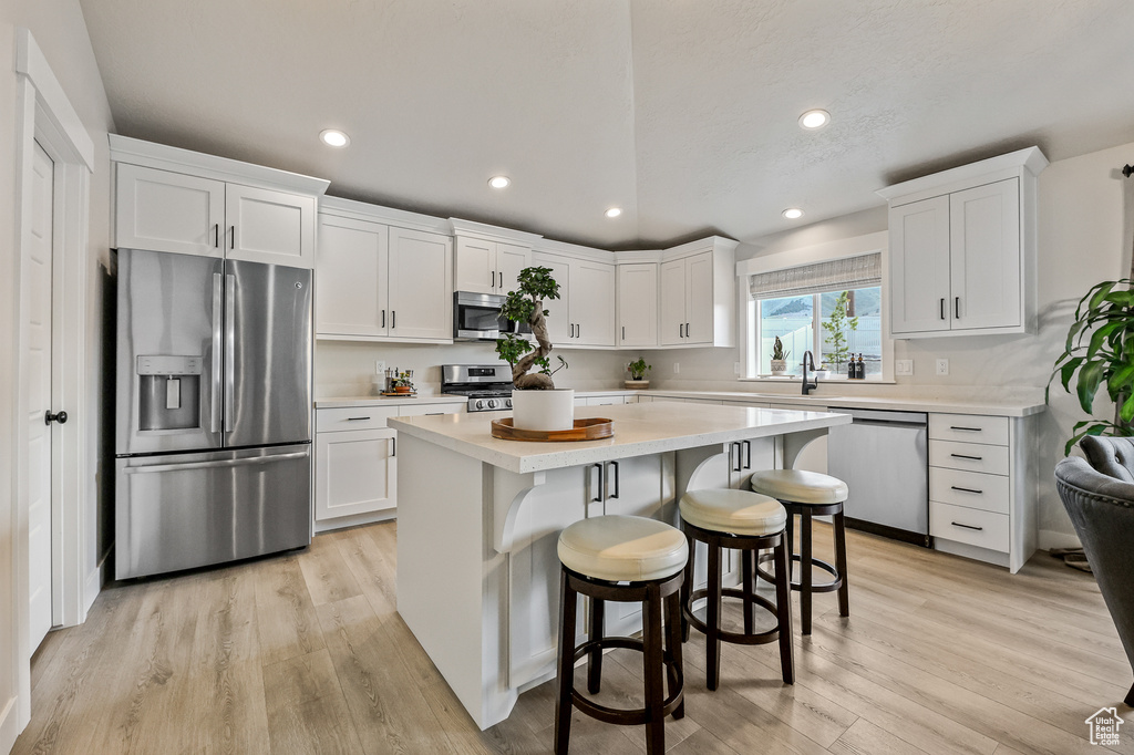 Kitchen with light hardwood / wood-style flooring, white cabinetry, and appliances with stainless steel finishes