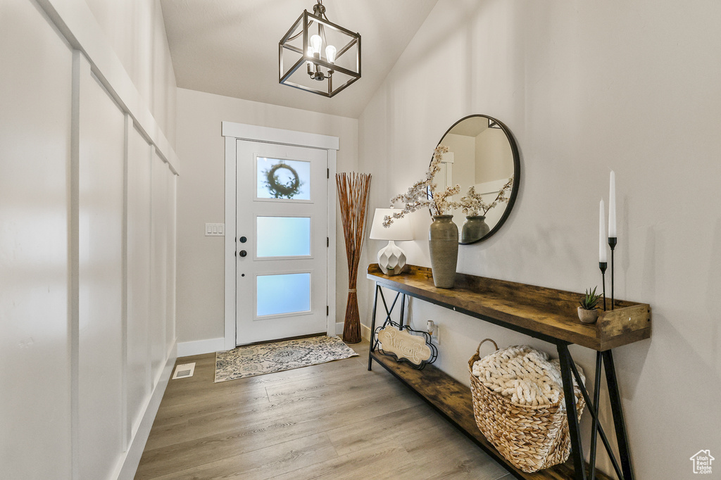 Foyer featuring an inviting chandelier, light hardwood / wood-style floors, and lofted ceiling