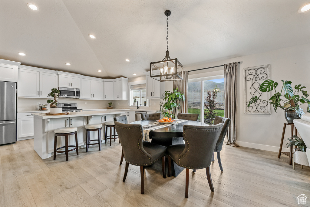 Dining area featuring a chandelier, vaulted ceiling, and light hardwood / wood-style flooring