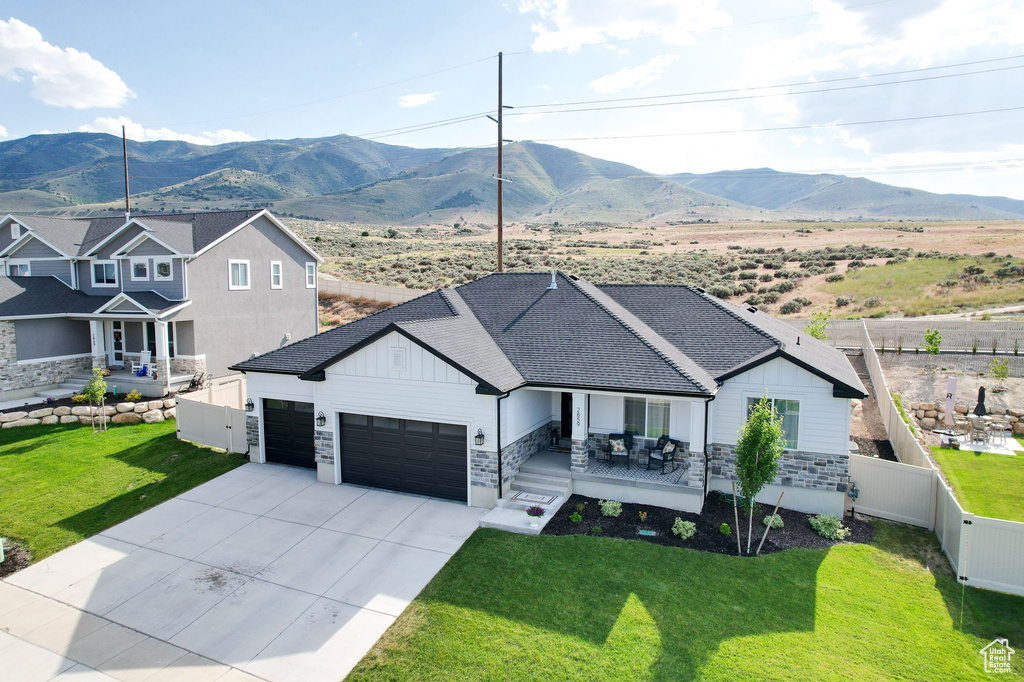 View of front of house featuring a garage, a mountain view, and a front lawn