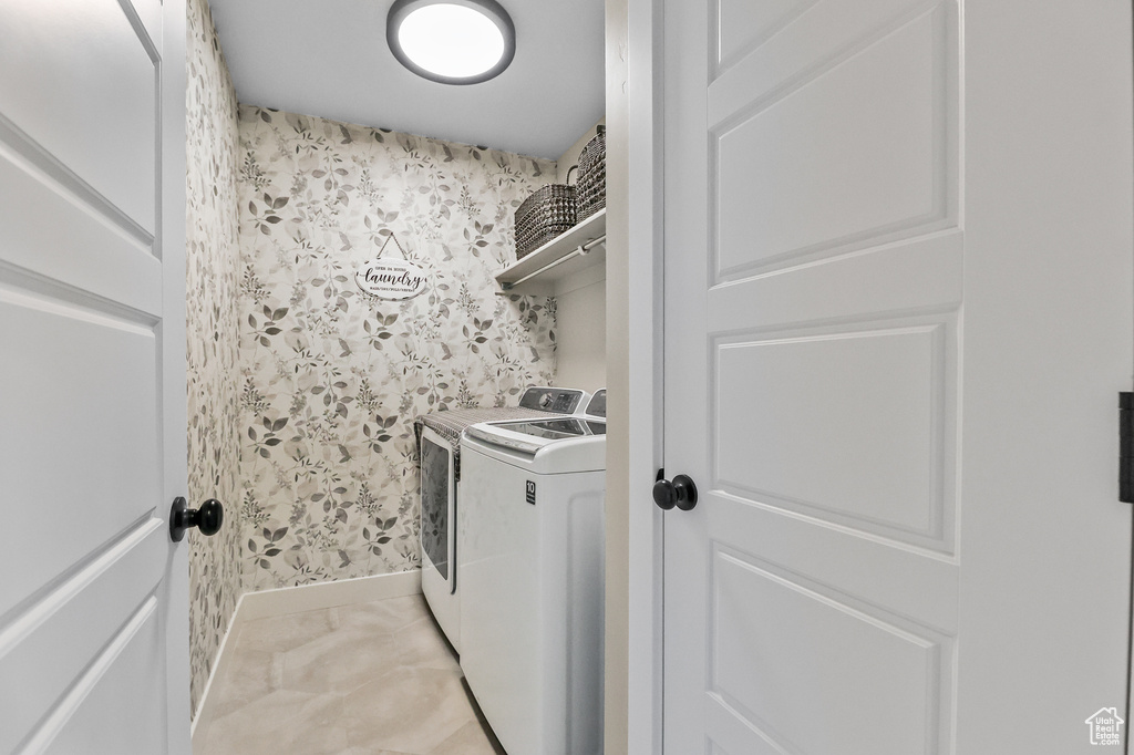 Clothes washing area featuring washer and clothes dryer and light tile floors