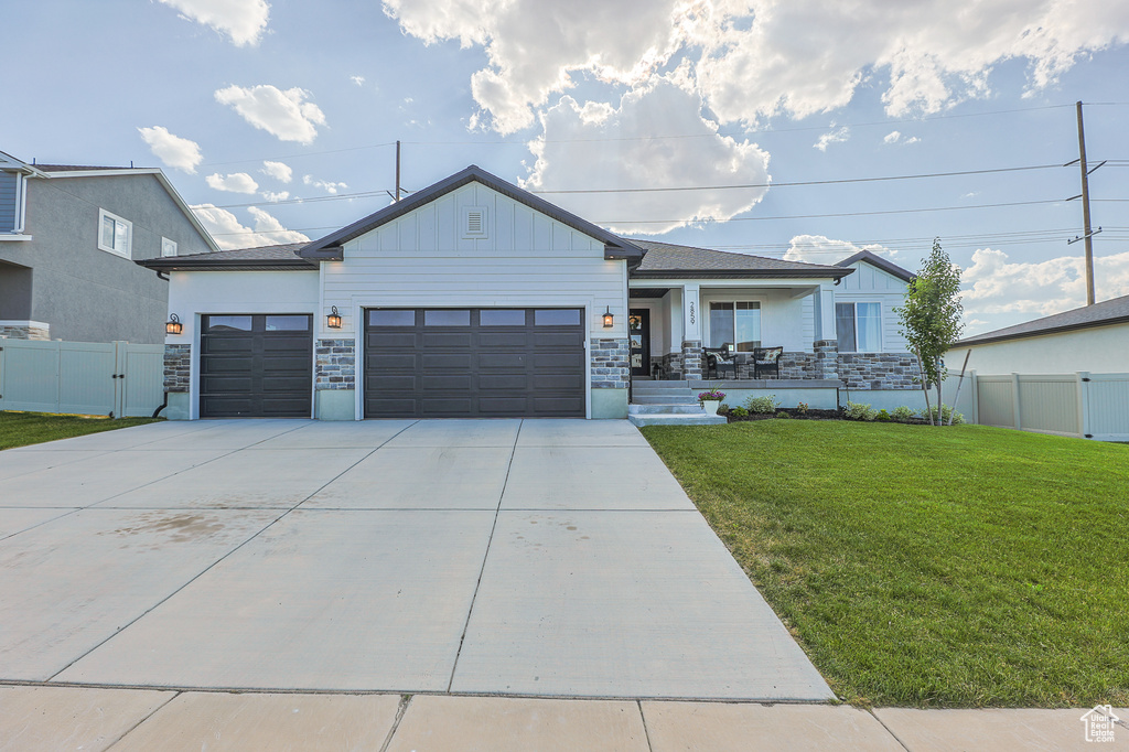 View of front of home with covered porch, a garage, and a front lawn