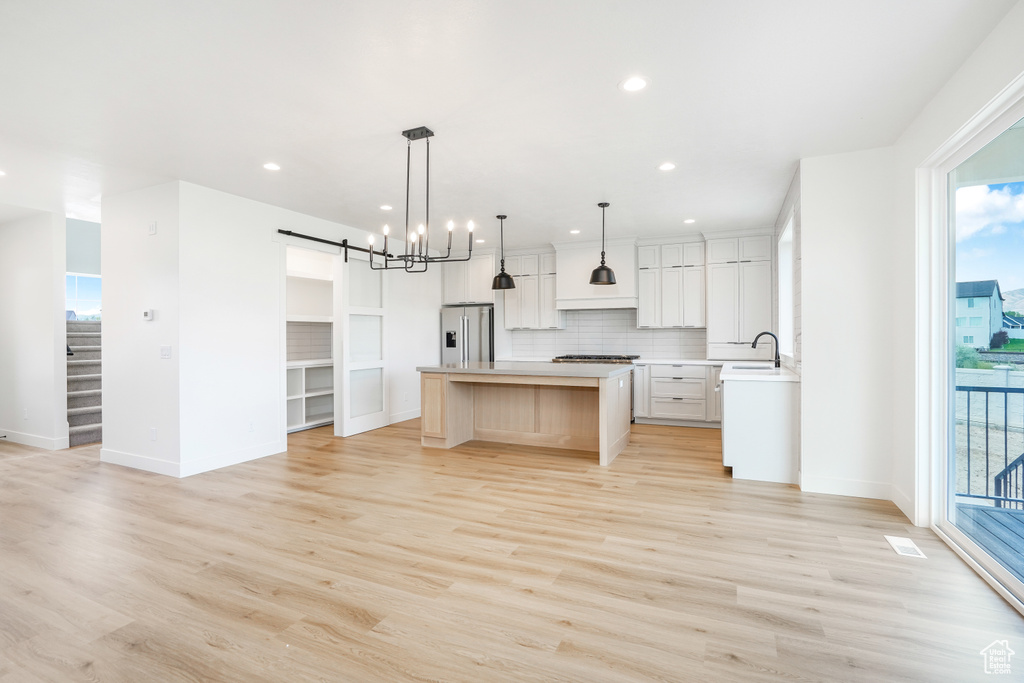 Kitchen with light hardwood / wood-style floors, a healthy amount of sunlight, high end refrigerator, and a kitchen island