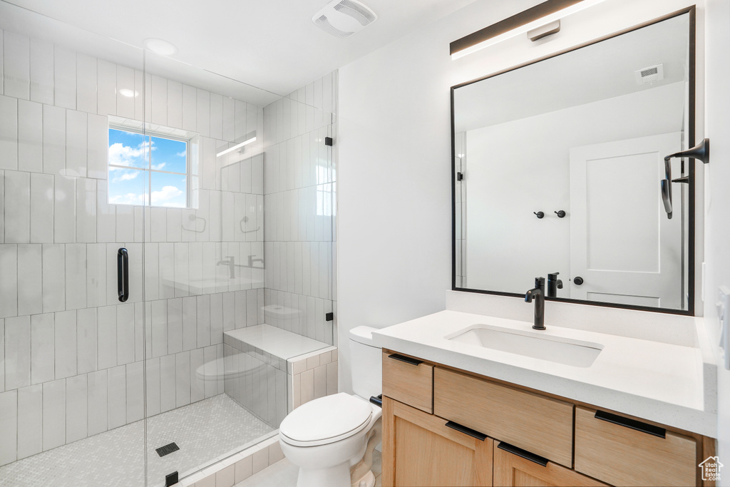 Bathroom featuring an enclosed shower, oversized vanity, and toilet