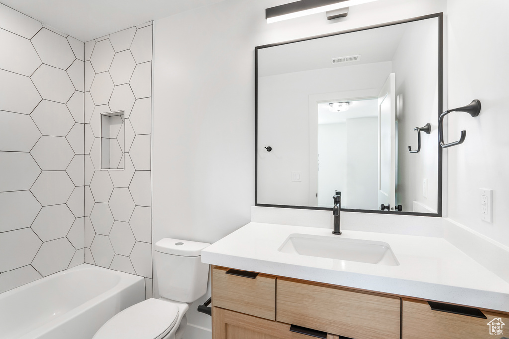 Full bathroom with tiled shower / bath combo, toilet, and vanity