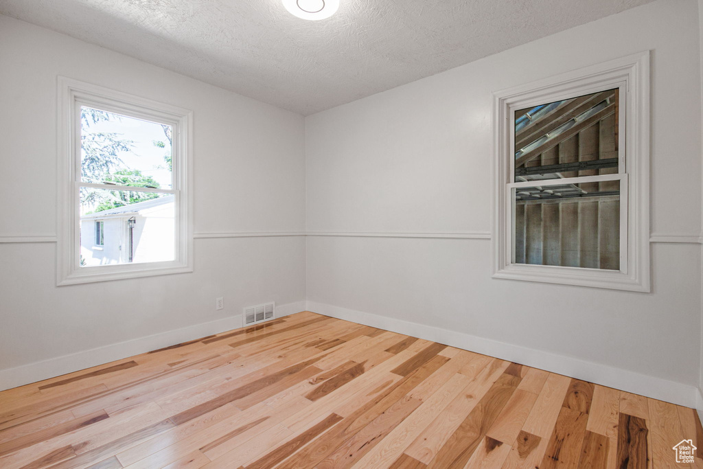 Empty room with hardwood / wood-style floors and a textured ceiling