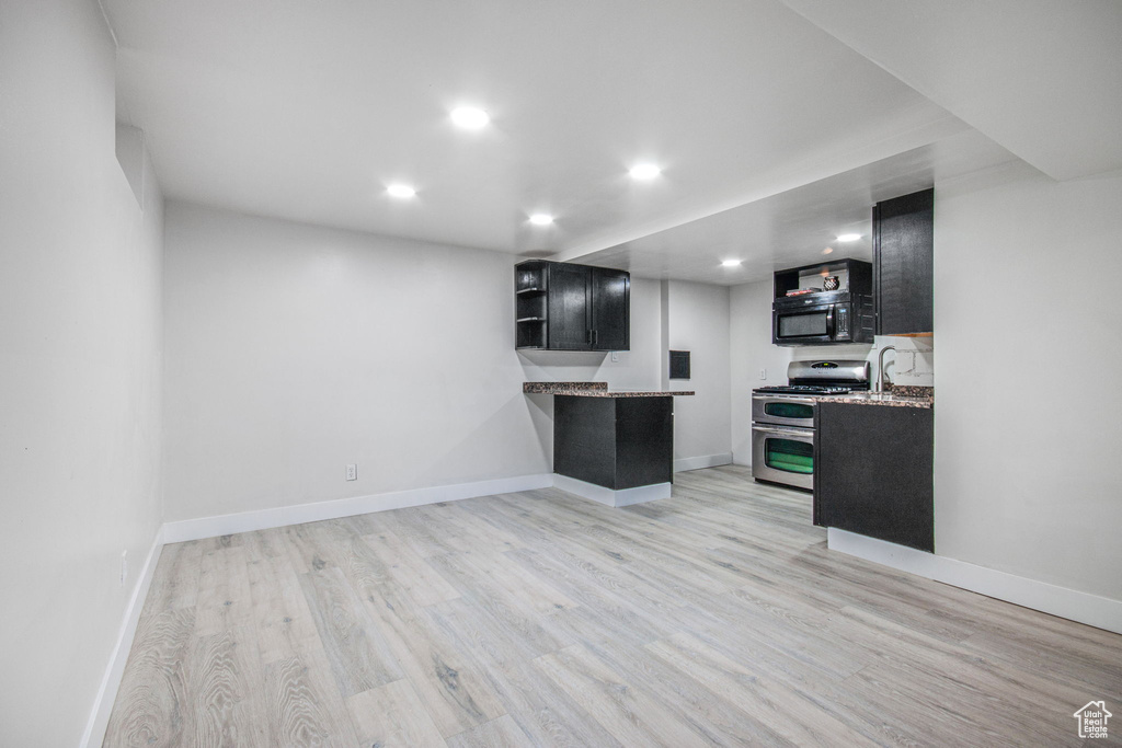 Kitchen with light stone counters, light hardwood / wood-style flooring, and range with two ovens