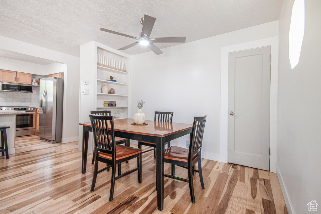 Dining area featuring light hardwood / wood-style floors, a textured ceiling, built in shelves, and ceiling fan