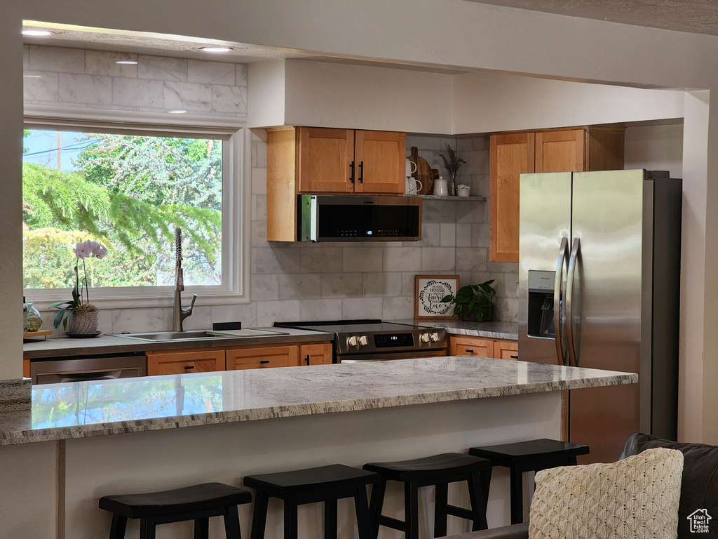 Kitchen with appliances with stainless steel finishes, tasteful backsplash, and light stone counters