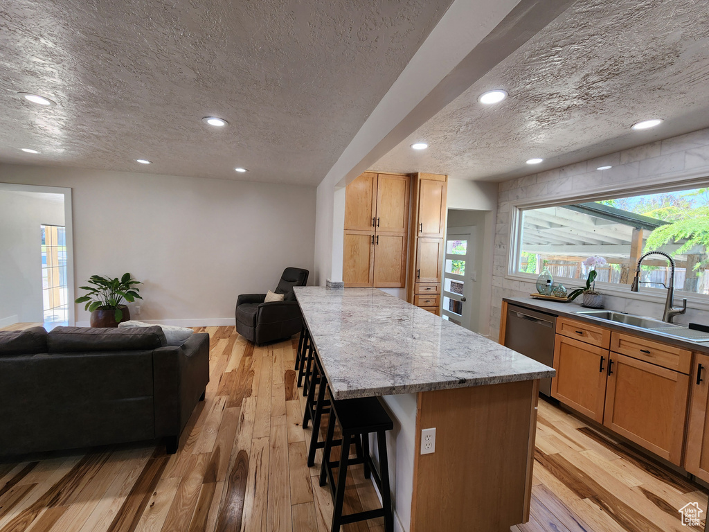 Kitchen featuring sink, a breakfast bar, light wood-type flooring, and a kitchen island