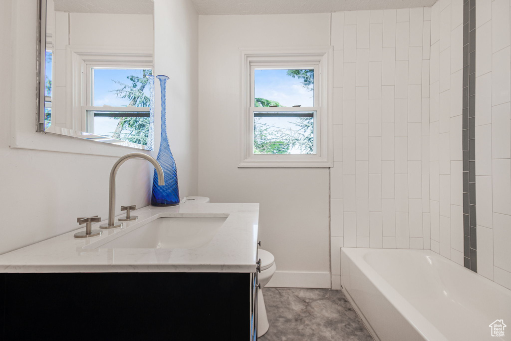 Full bathroom with washtub / shower combination, vanity, toilet, and tile floors