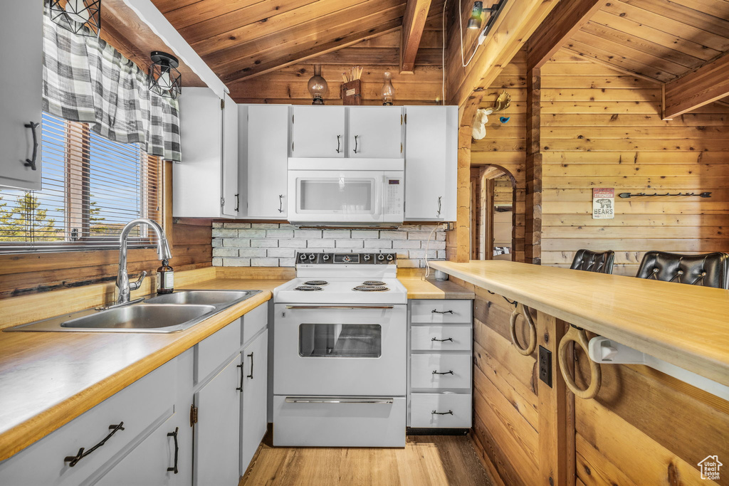 Kitchen featuring white appliances, vaulted ceiling, wood ceiling, and wood walls