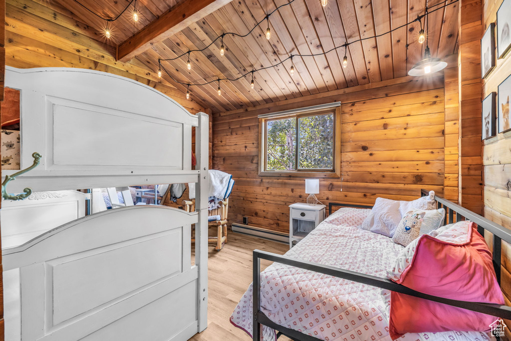 Bedroom with a baseboard heating unit, light wood-type flooring, beamed ceiling, wood walls, and wood ceiling