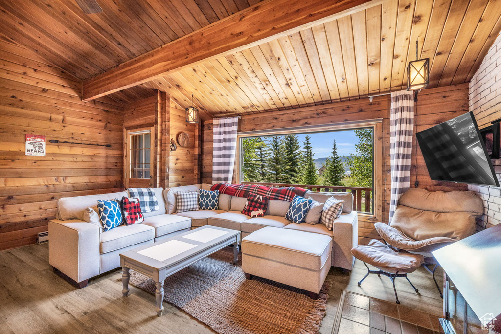 Living room with wood ceiling, wooden walls, lofted ceiling with beams, and wood-type flooring