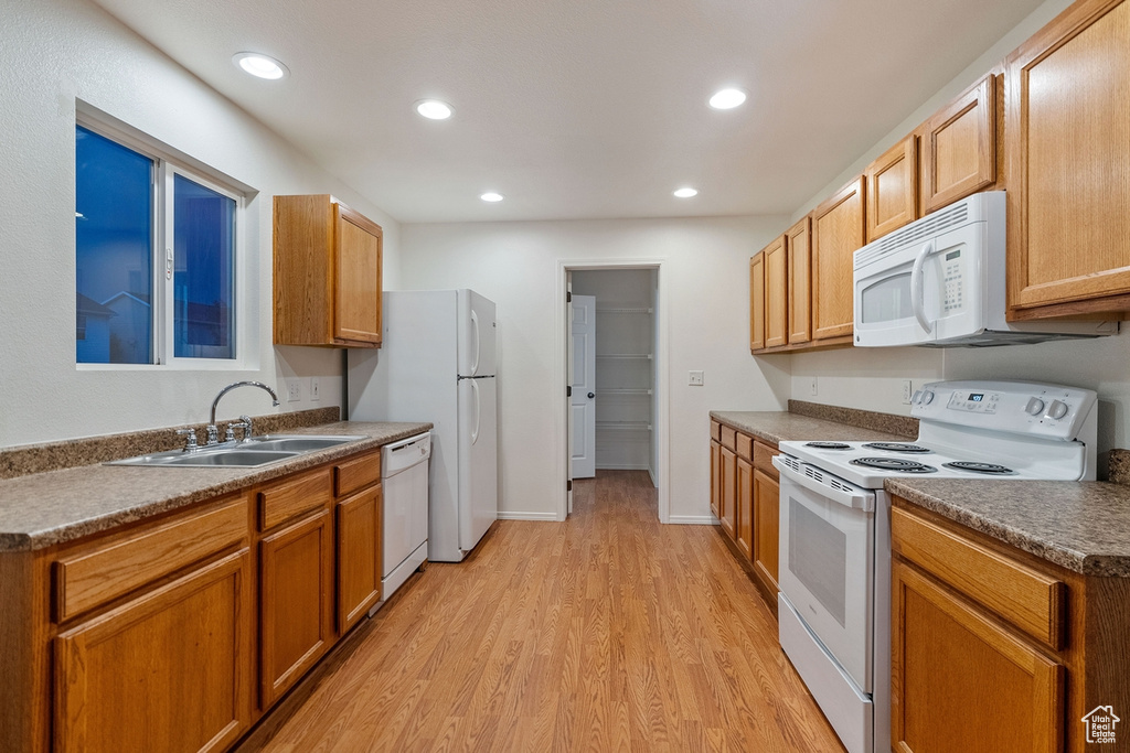 Kitchen with sink, white appliances, and light wood-type flooring