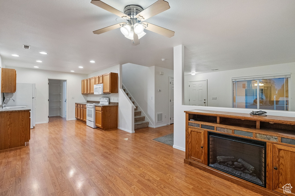 Kitchen with light hardwood / wood-style floors, white appliances, sink, and ceiling fan