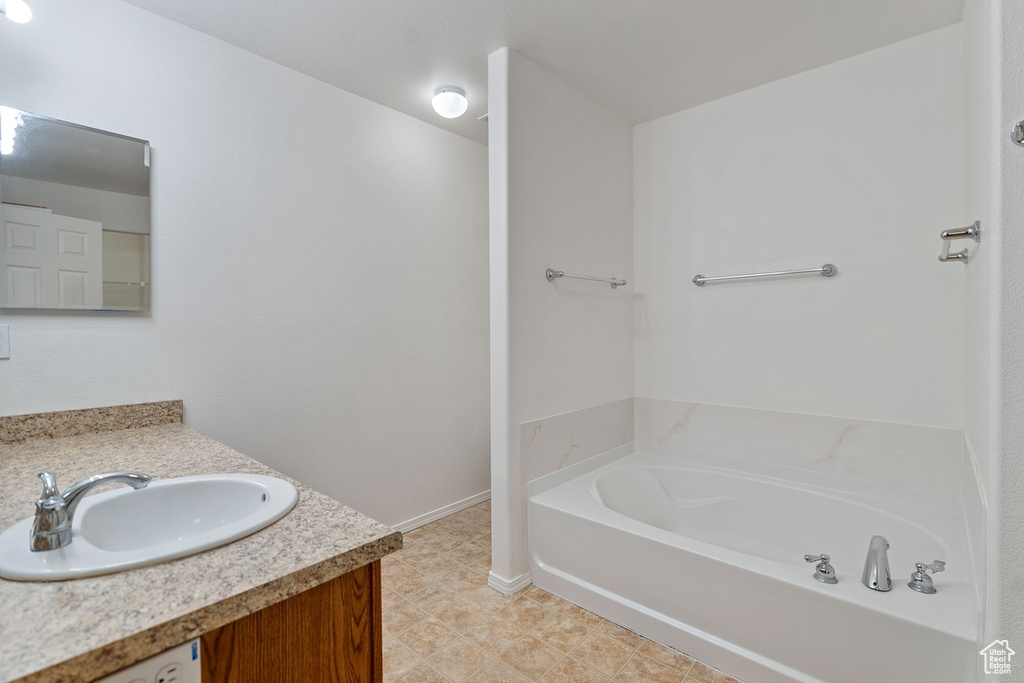 Bathroom featuring vanity, a washtub, and tile patterned flooring