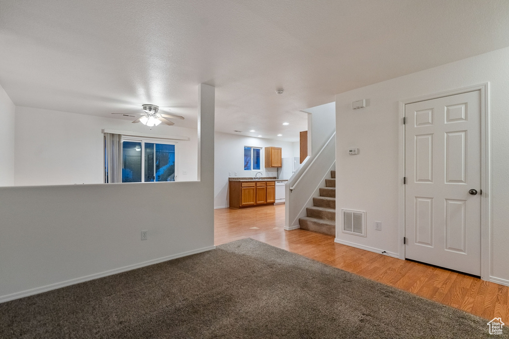 Unfurnished living room featuring ceiling fan, sink, and light hardwood / wood-style flooring