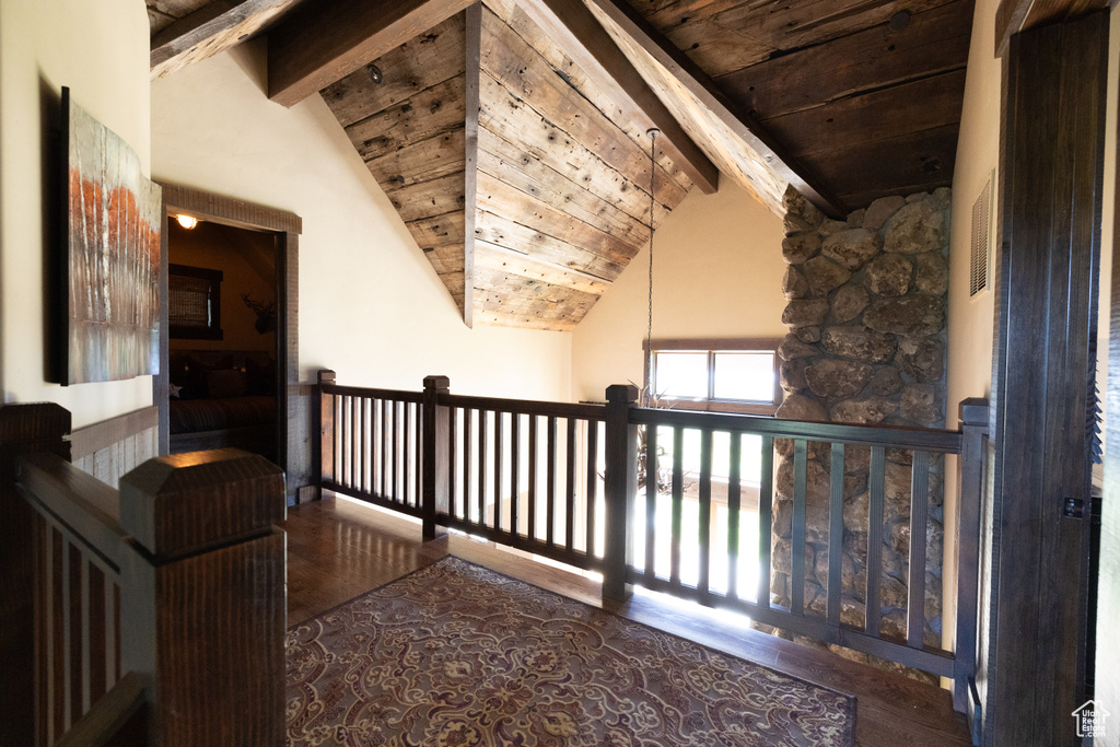 Corridor with wooden ceiling, vaulted ceiling with beams, and wood-type flooring