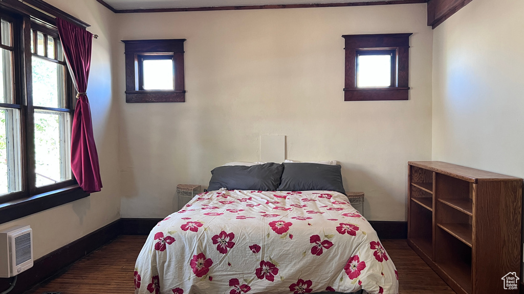 Bedroom featuring an AC wall unit, dark hardwood / wood-style floors, and multiple windows