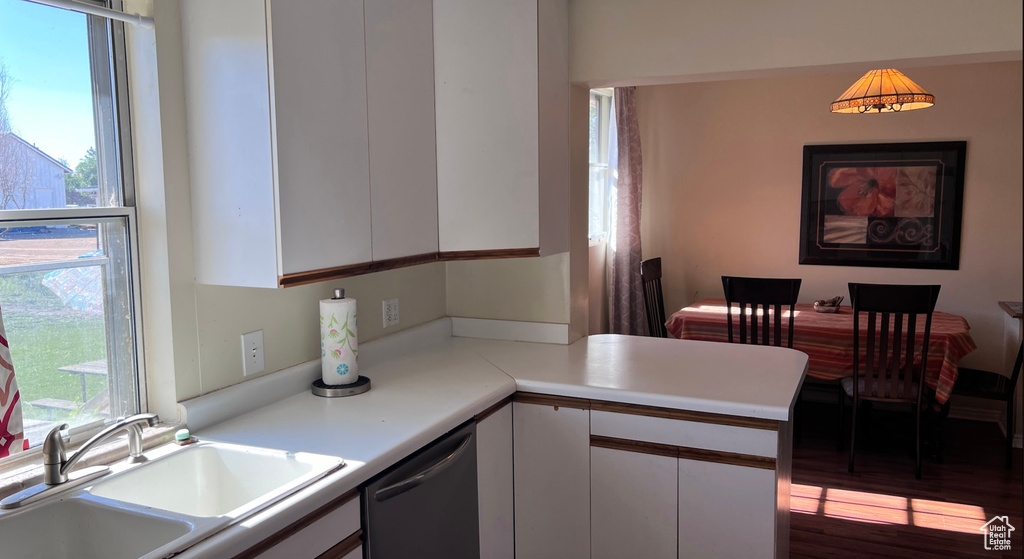 Kitchen featuring sink, white cabinetry, hardwood / wood-style flooring, and stainless steel dishwasher