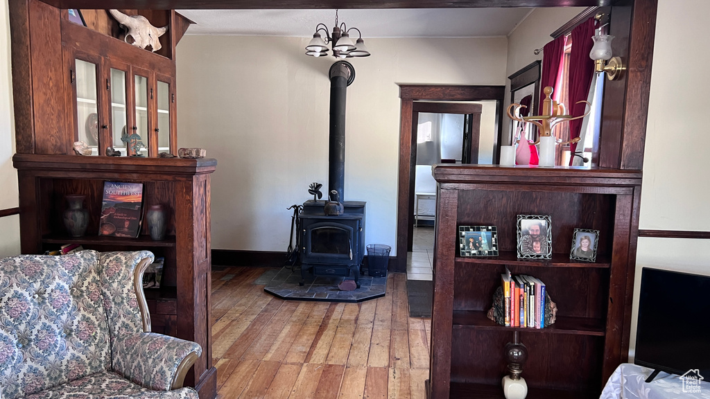 Living room with an inviting chandelier, a wood stove, and hardwood / wood-style floors