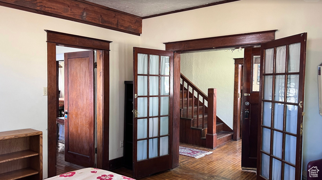 Unfurnished bedroom featuring a textured ceiling, dark wood-type flooring, ornamental molding, and french doors