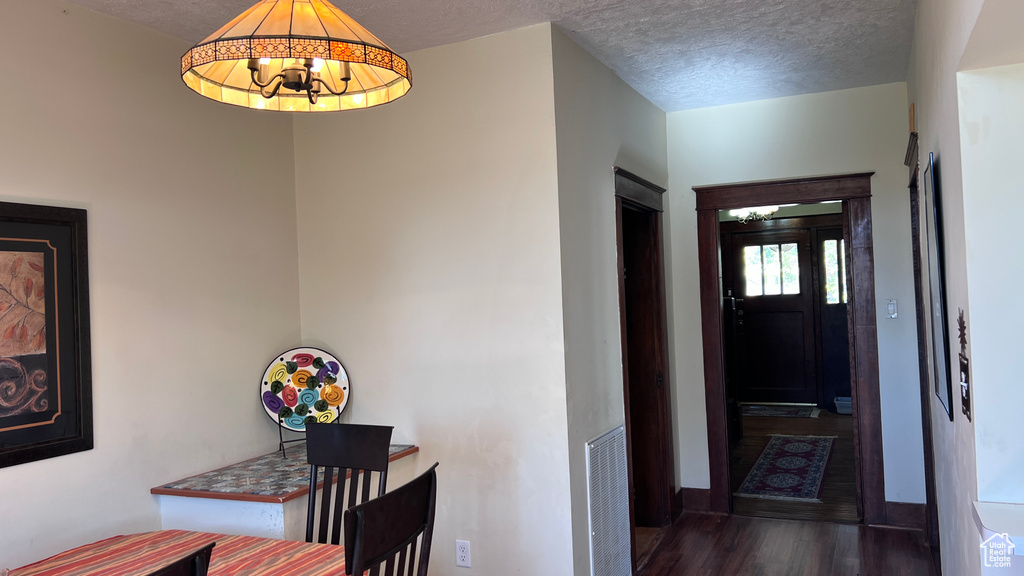 Hallway with dark hardwood / wood-style floors, a notable chandelier, and a textured ceiling