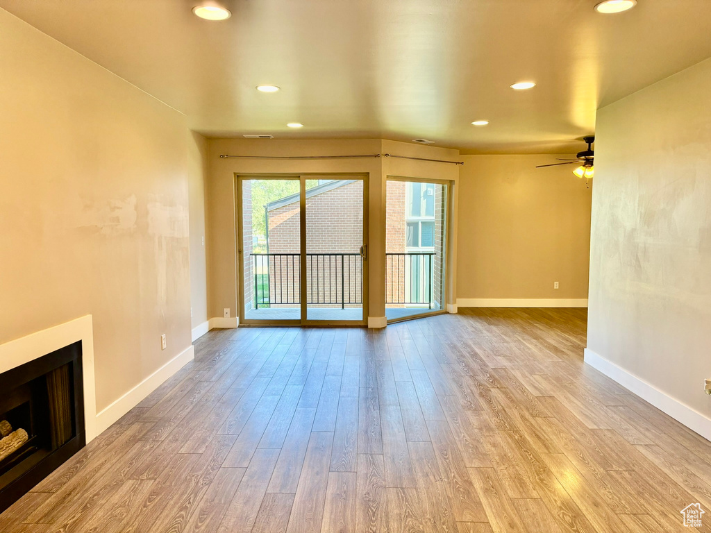 Unfurnished living room featuring ceiling fan and light hardwood / wood-style flooring