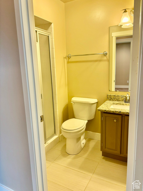 Bathroom with a shower with door, toilet, tile floors, and large vanity