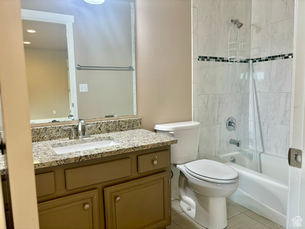 Full bathroom featuring tile floors, large vanity, toilet, and tiled shower / bath combo