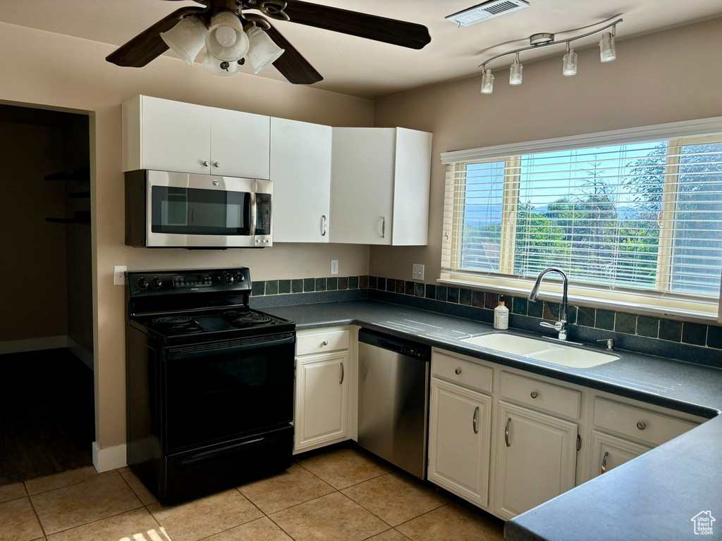 Kitchen featuring stainless steel appliances, ceiling fan, rail lighting, white cabinets, and sink