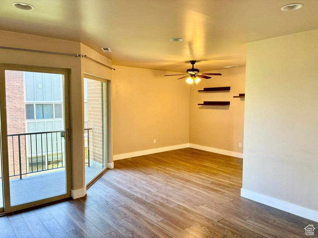 Empty room with hardwood / wood-style floors and ceiling fan