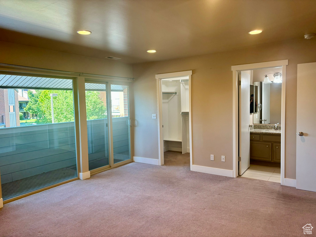 Unfurnished bedroom with a closet, light colored carpet, and a spacious closet