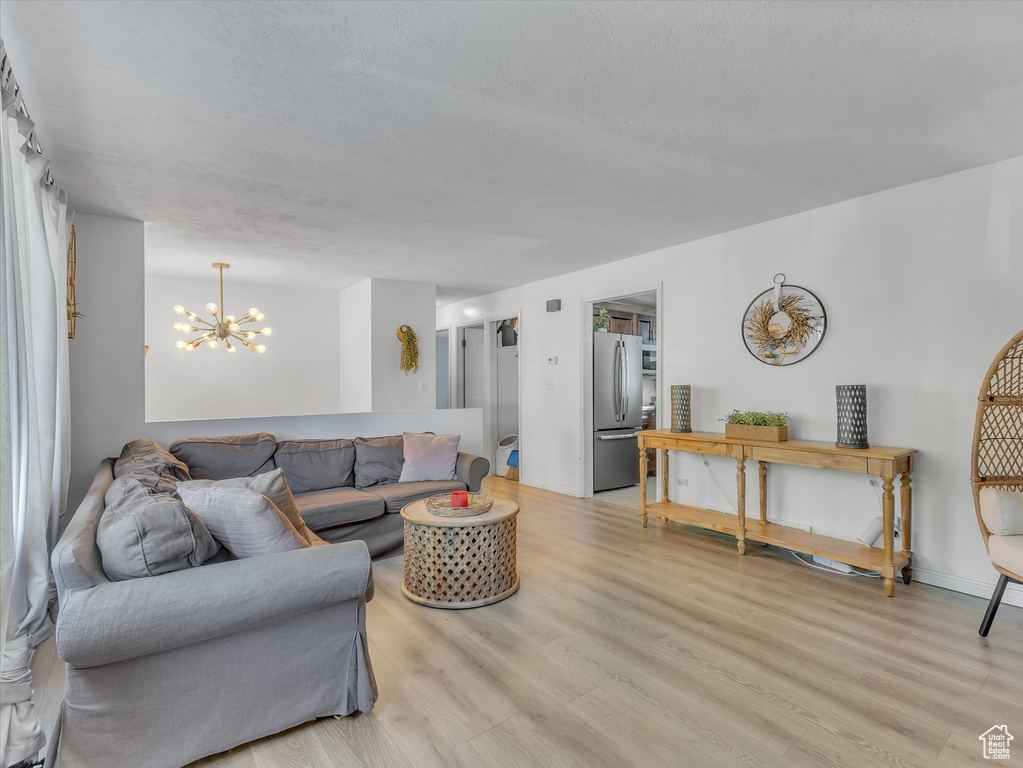 Living room with light hardwood / wood-style floors and a chandelier