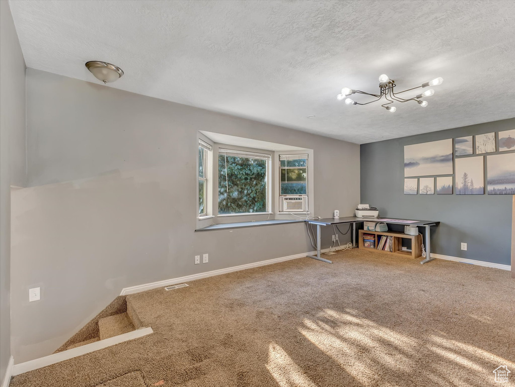 Unfurnished office featuring a chandelier, a textured ceiling, and carpet