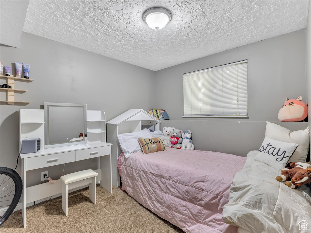 Bedroom featuring a textured ceiling and light colored carpet