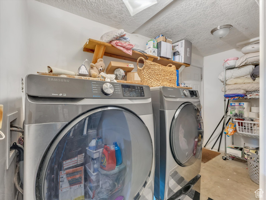 Clothes washing area featuring a textured ceiling, washing machine and dryer, and washer hookup