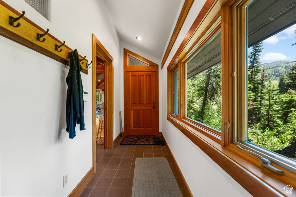 Corridor with vaulted ceiling and dark tile floors
