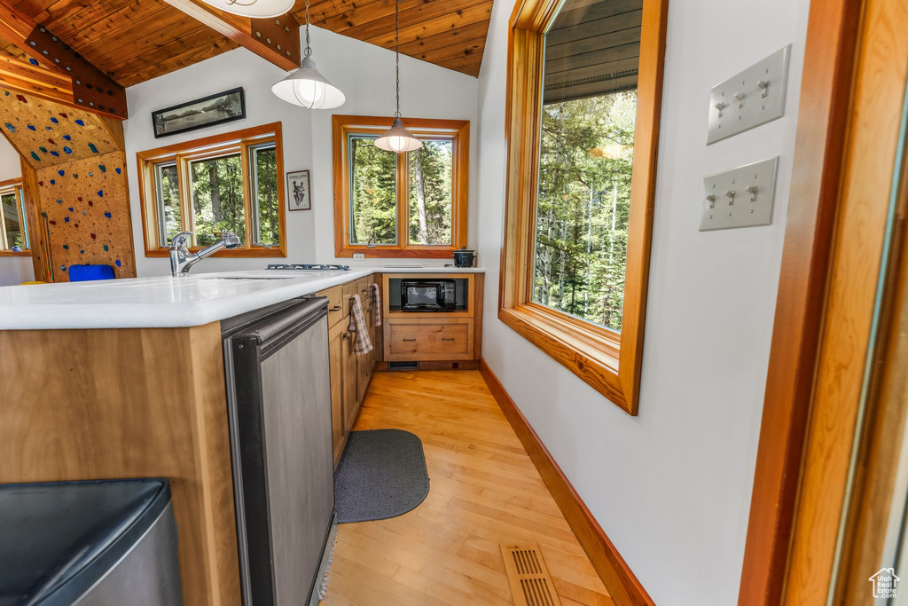 Kitchen featuring hanging light fixtures, lofted ceiling with beams, light hardwood / wood-style flooring, stainless steel dishwasher, and wood ceiling