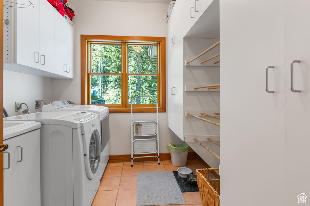 Clothes washing area with washing machine and clothes dryer, hookup for an electric dryer, cabinets, and light tile floors