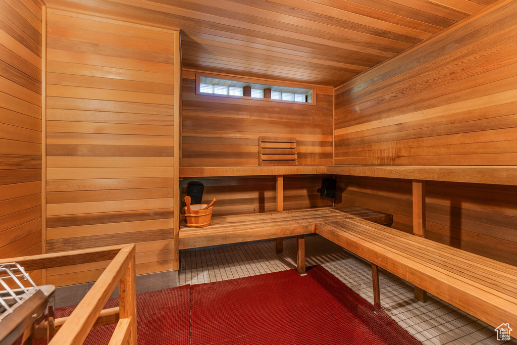 View of sauna / steam room with wooden ceiling, tile flooring, and wood walls